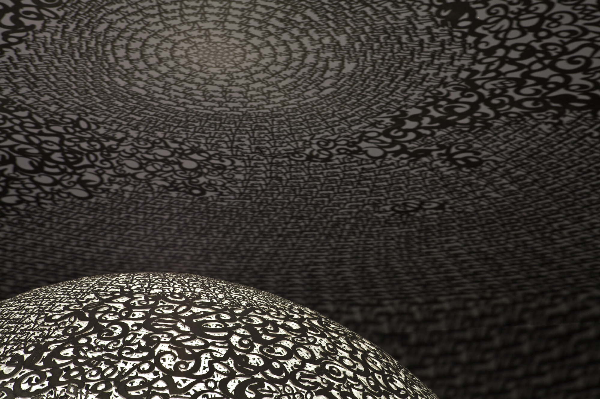 Interior view inside the openwork globe looking up, the perforated dome casting patterned light, Globe N°1.