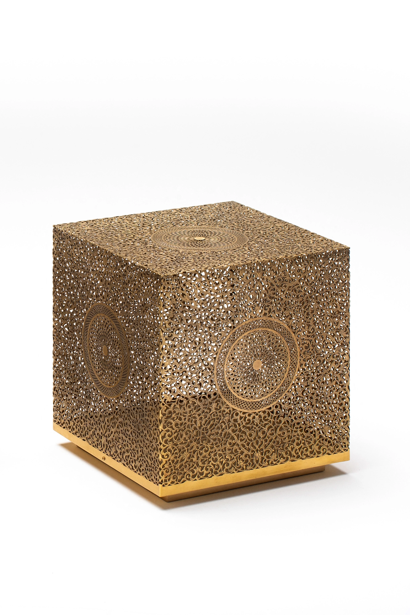 A pierced golden cube lamp on a small base, photographed unlit against a white background.