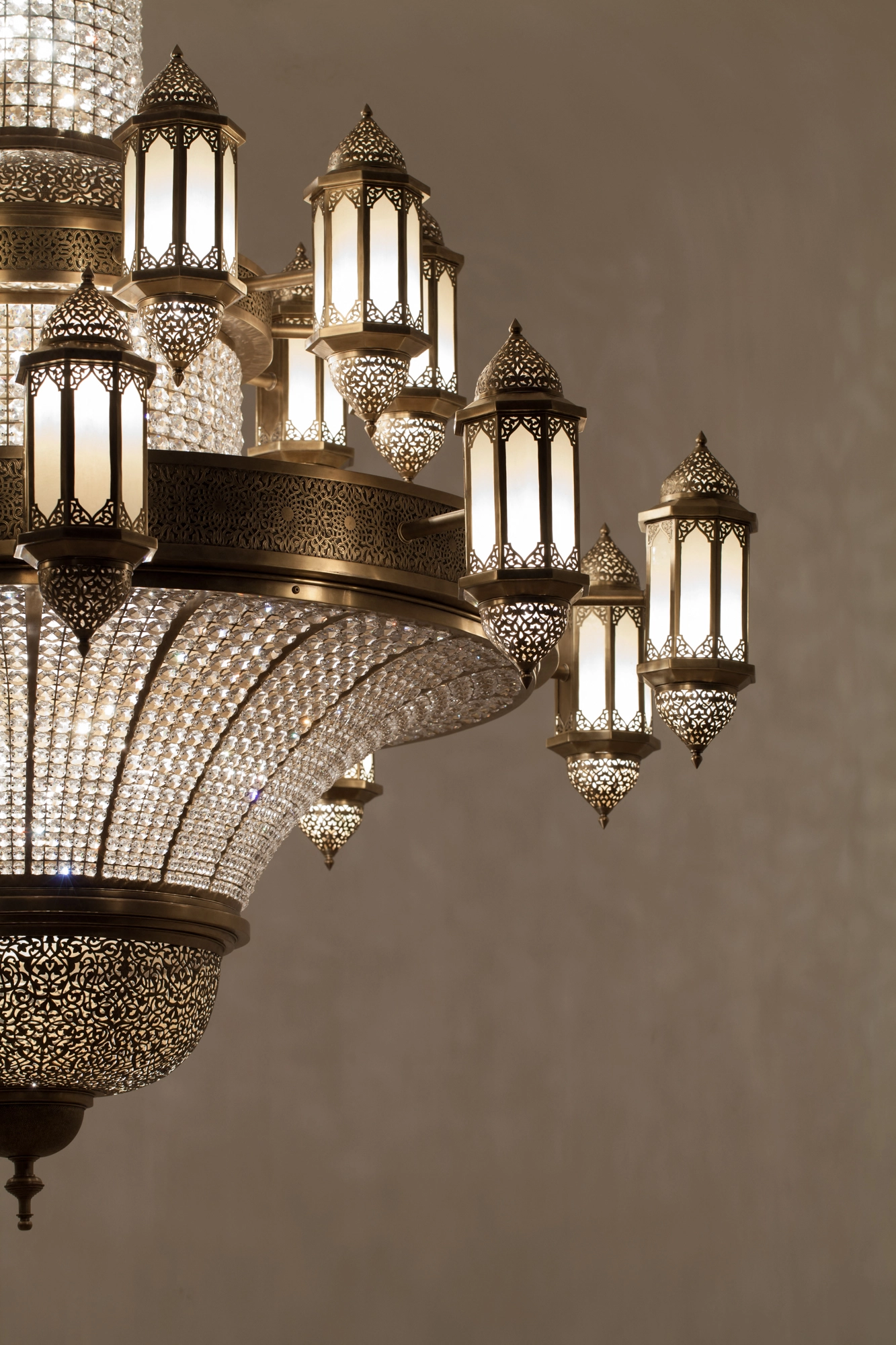 An angled view of a tiered crystal-and-brass chandelier, its rows of pierced lanterns glowing warmly.