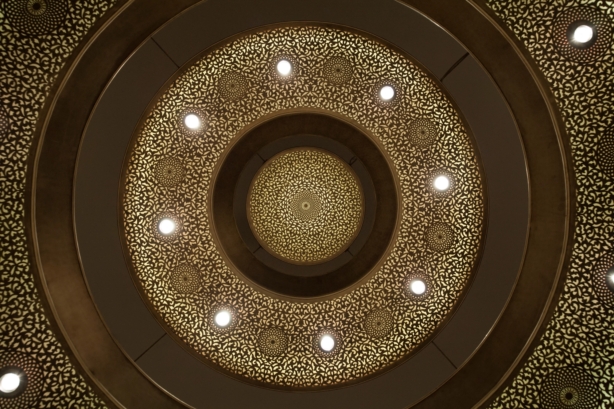 A triple-ring pierced chandelier viewed from directly below, its concentric rings set with small downlights.