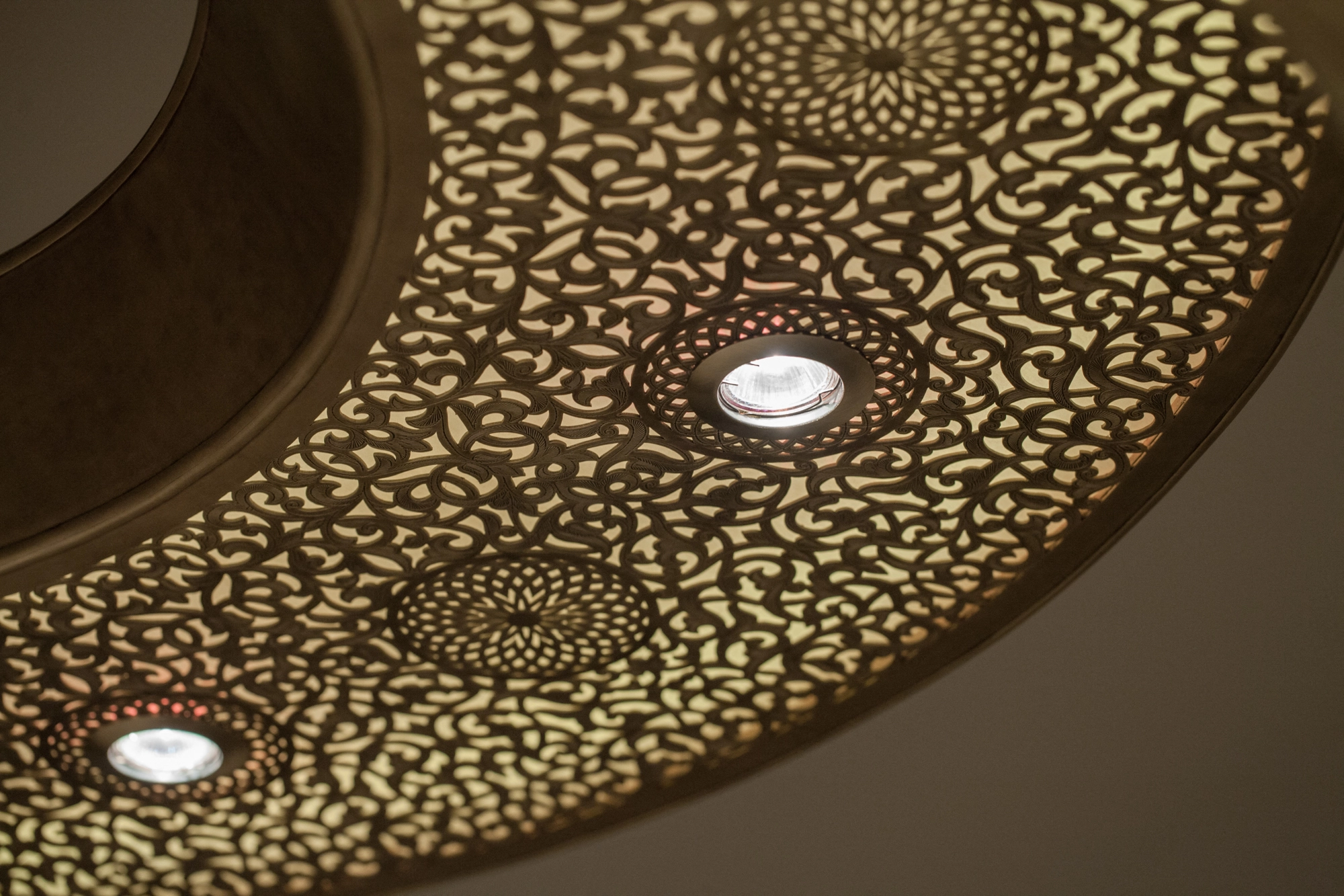 Close-up of a chandelier's pierced metal ring edge set with small recessed downlights.
