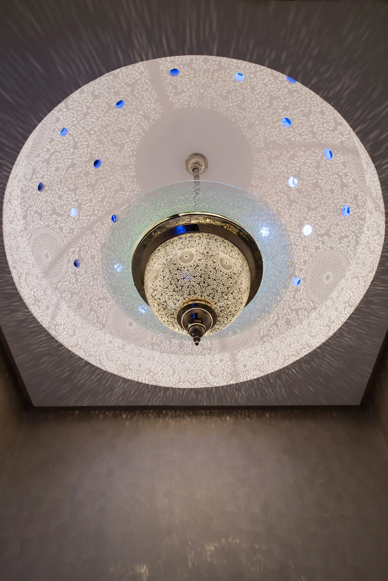 View up into a domed cupola with a sparkling pierced globe fixture at its center, ringed by small blue accent lights.