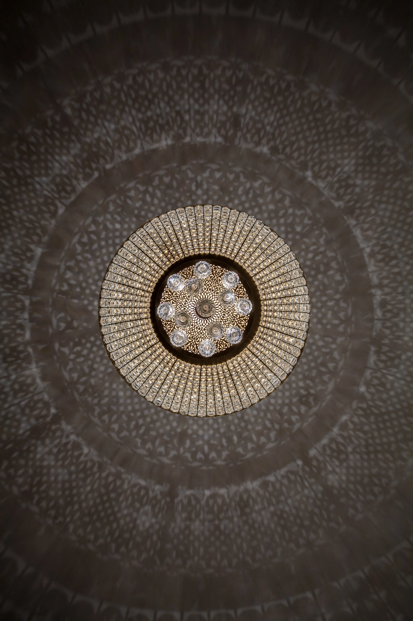 A crystal chandelier viewed from directly below, its beaded tiers forming concentric rings of light.