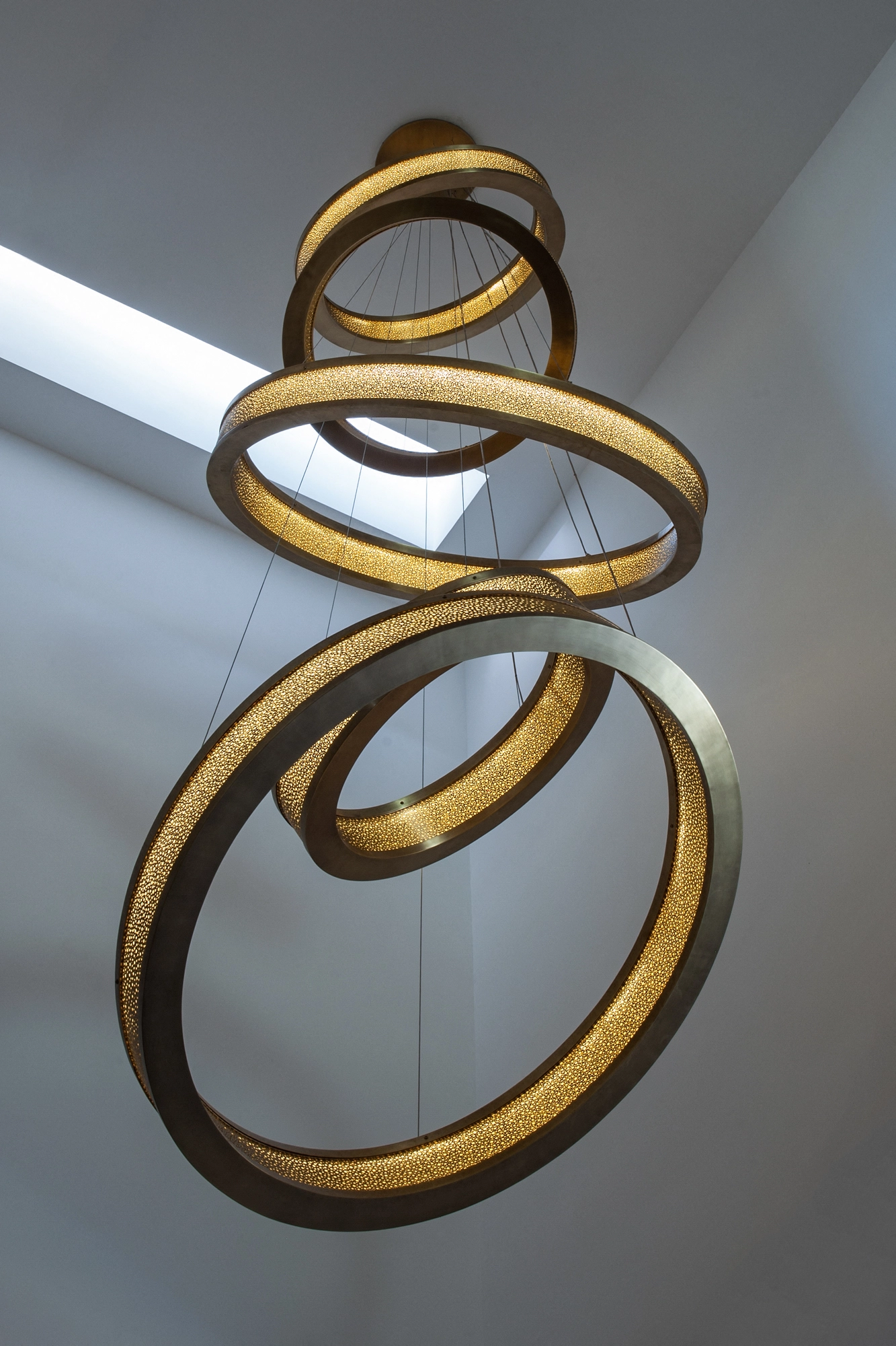 Several overlapping gold liquid-light rings cascading at angles against a bright wall.