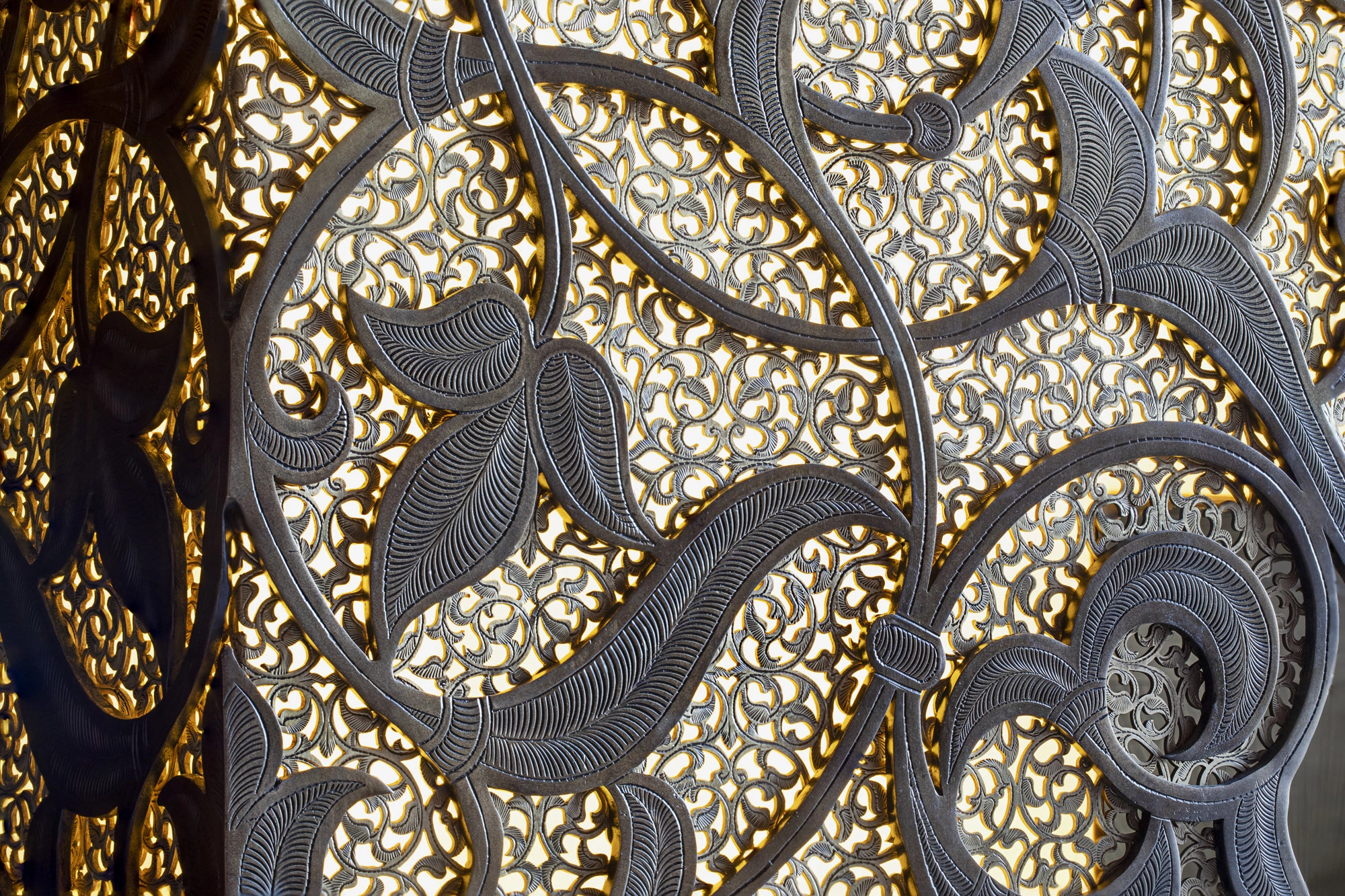 Close-up of a bespoke fireplace's gold and silver arabesque openwork texture.