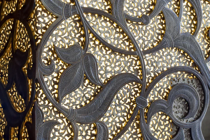 Close-up of a bespoke fireplace's gold and silver arabesque openwork texture.