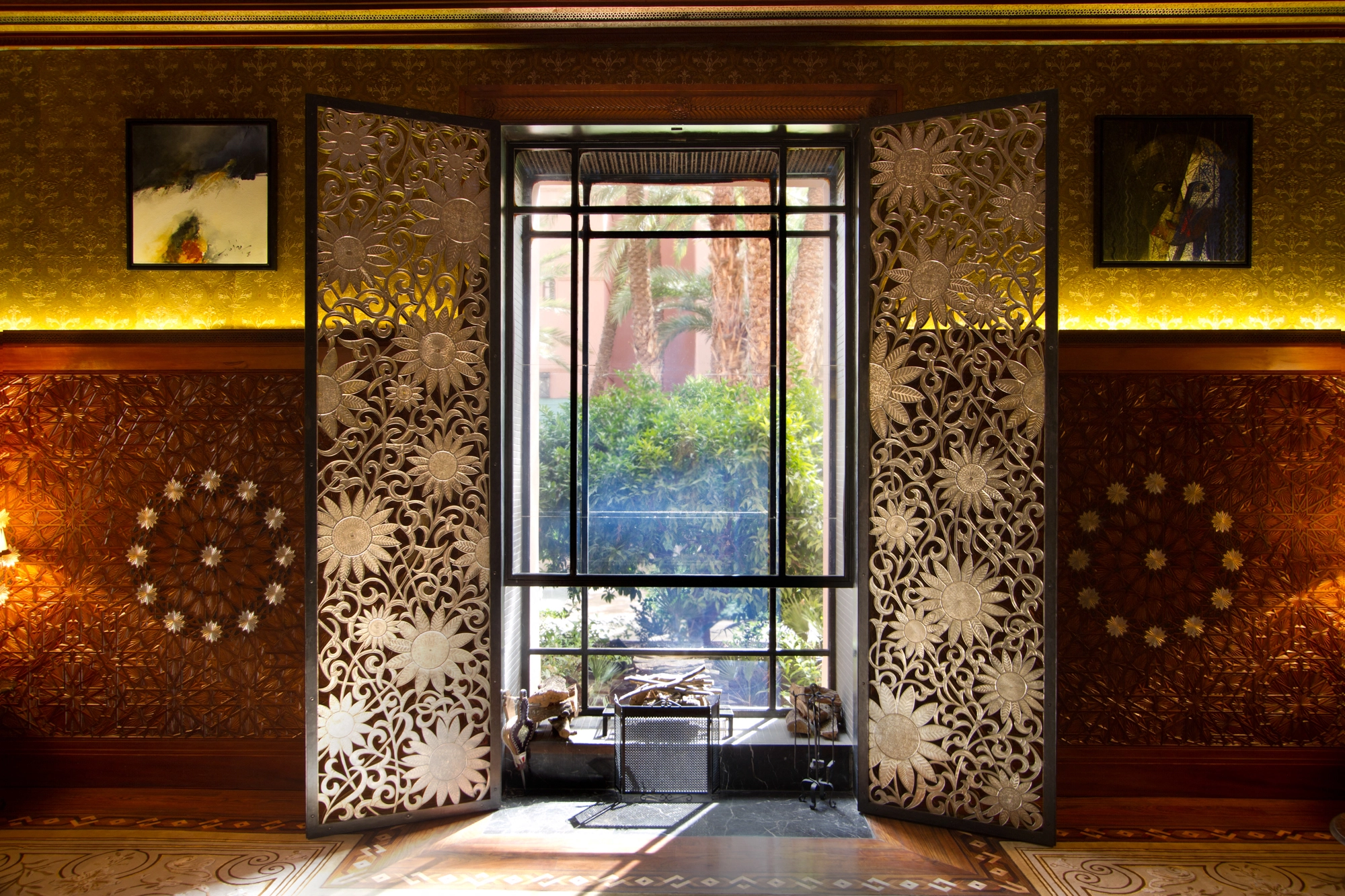 Room with art-deco pierced metal doors flanking a tall window against deep red walls.