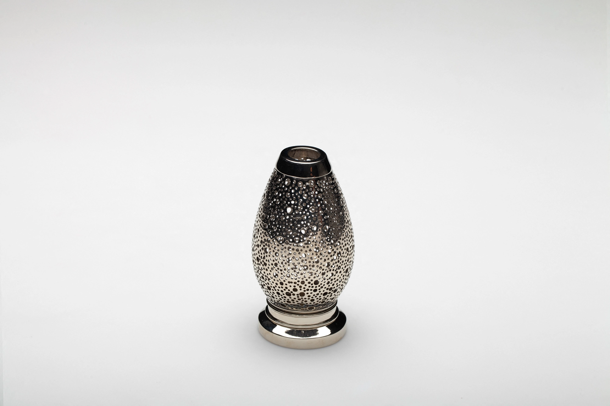 A small egg-shaped pierced metal candle holder in a silver finish, photographed against a white background.