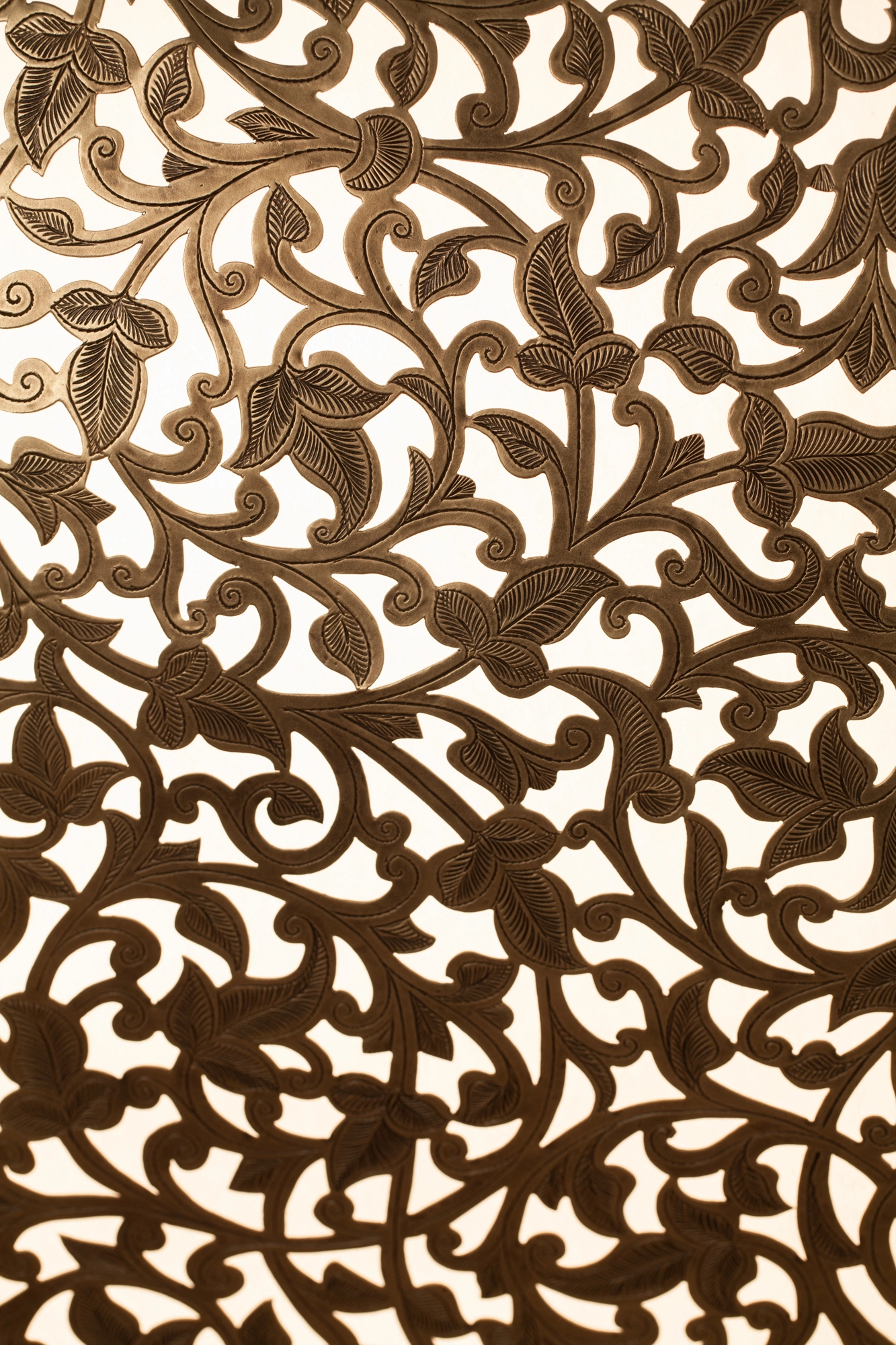 Close-up of a chandelier's pierced foliage-scroll pattern glowing warmly from within.