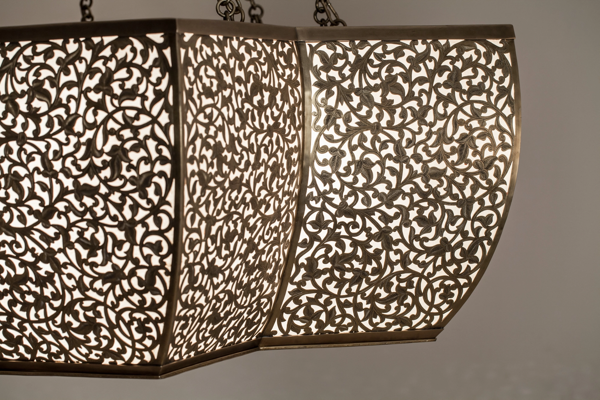 Close-up of a pierced octagonal chandelier's lobed edge scattering dotted light.