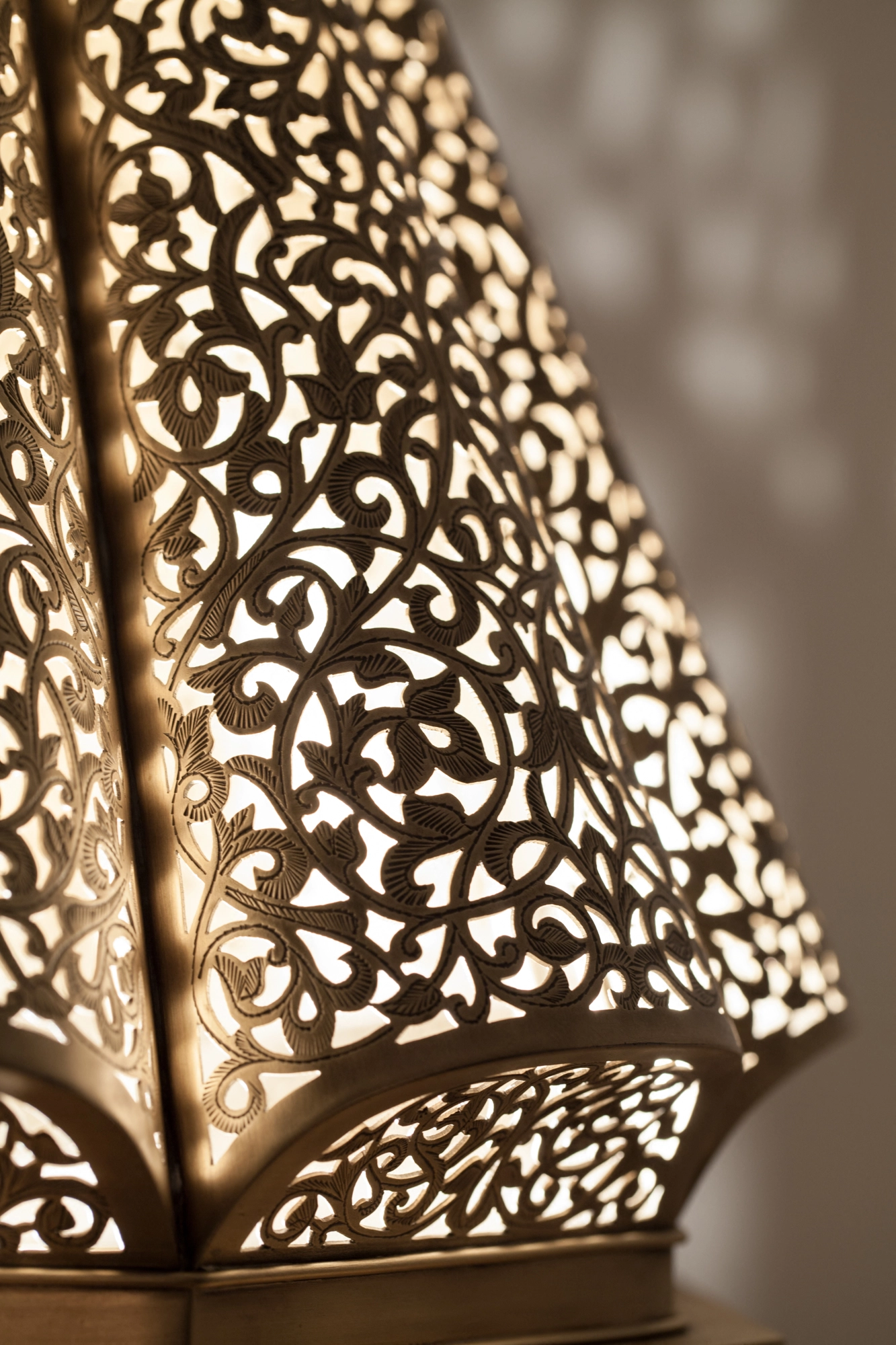 Close-up of a pierced lantern pendant's lower body glowing amid dotted patterns of light.