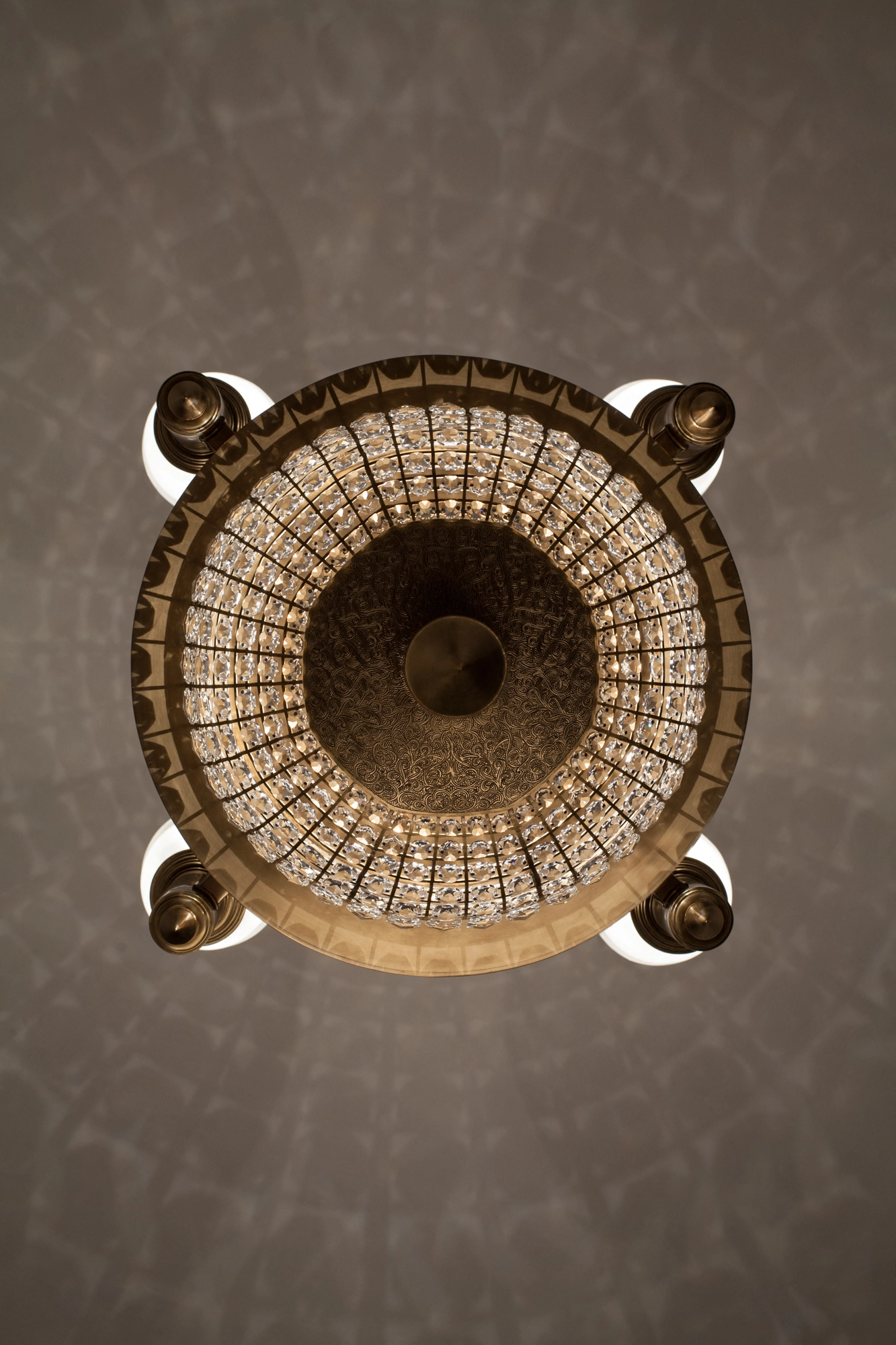 A crystal chandelier viewed from directly below, its beaded basket forming a bright circular ring.