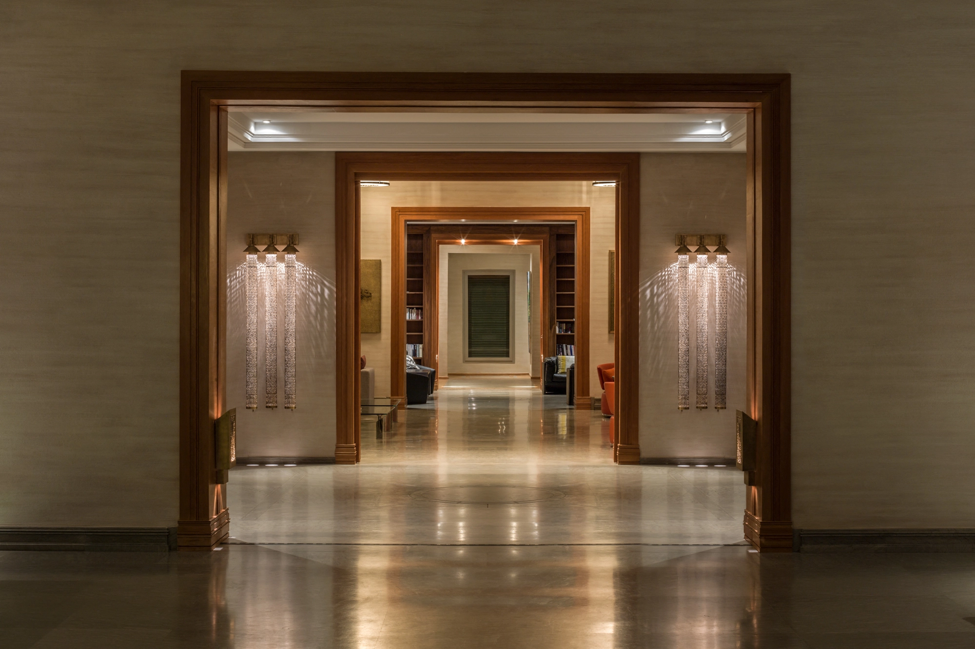 Long corridor lined with repeating pierced-cylinder wall lights glowing into the distance.