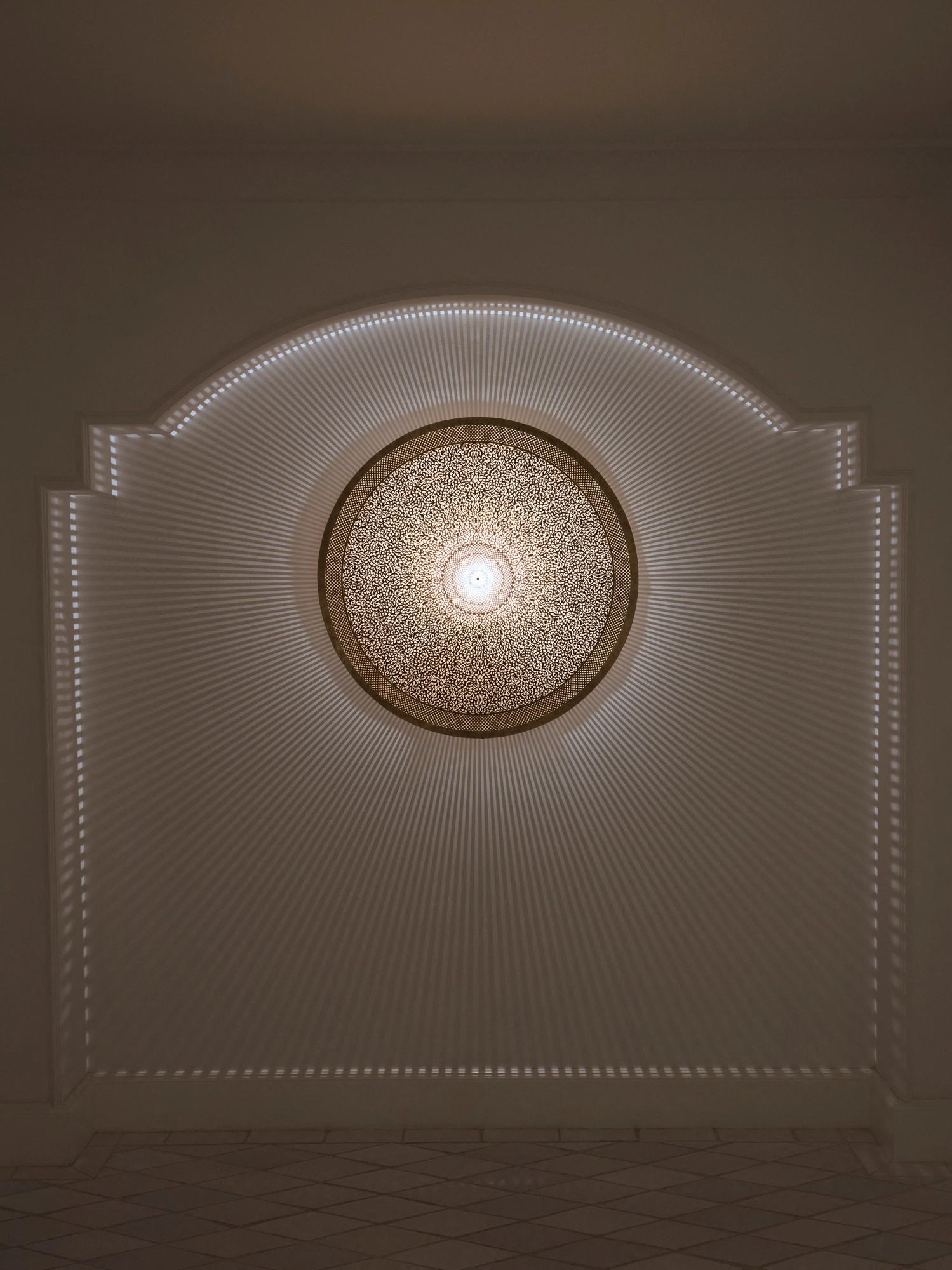Glowing circular medallion light centred on a softly lit arched wall panel.