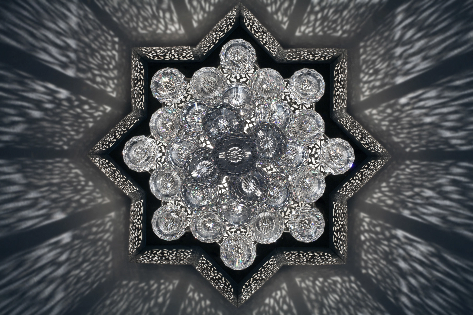 A star-shaped crystal ceiling light with a pierced floral center, mounted on the ceiling and viewed from below.