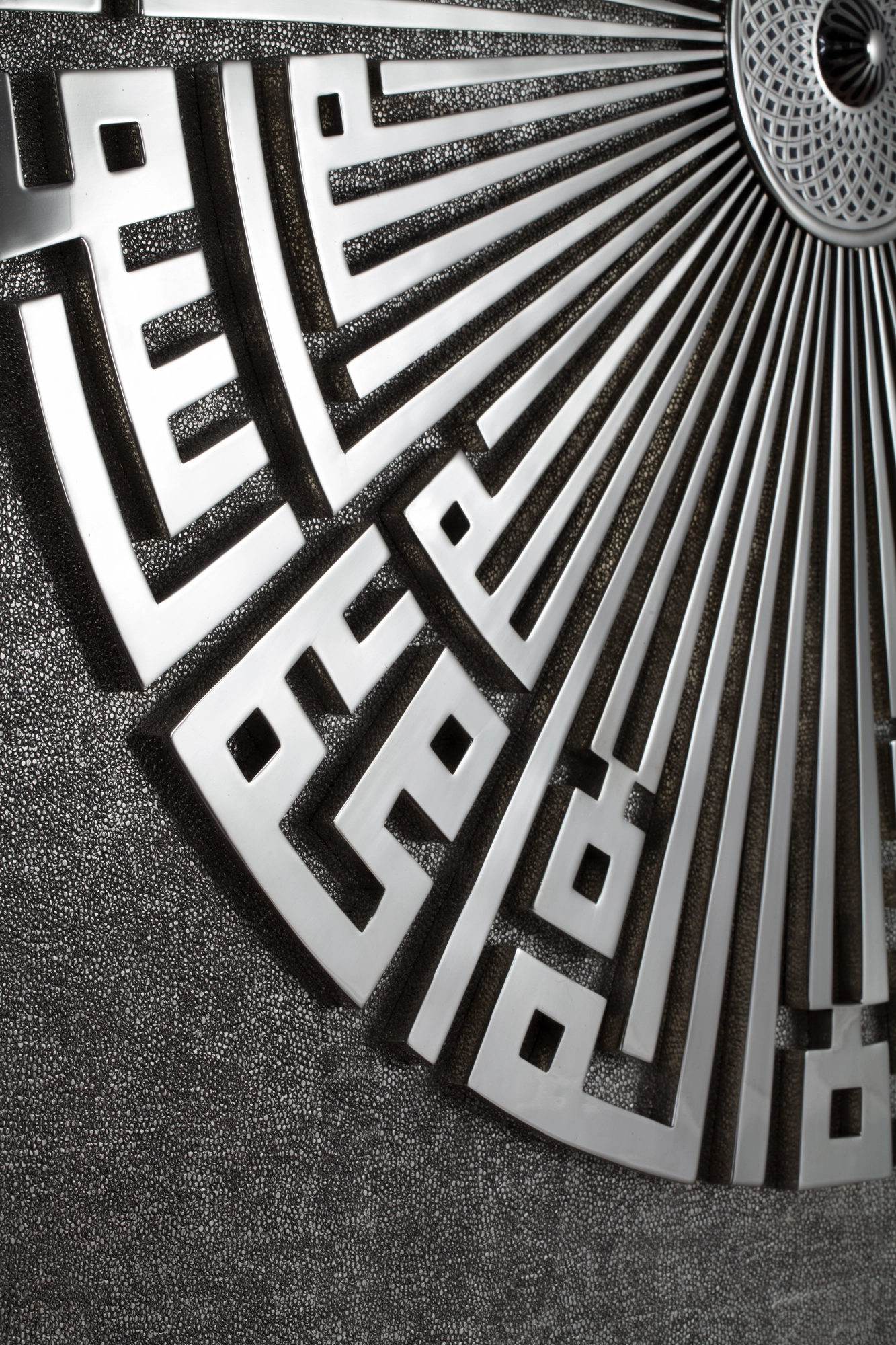 A quarter-circle fan of black geometric Kufic-style metalwork mounted on a grey surface.