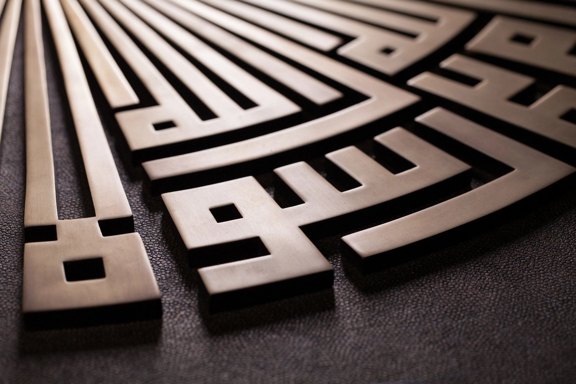 An angled view of a radiating fan of angular Kufic metalwork in raised relief.