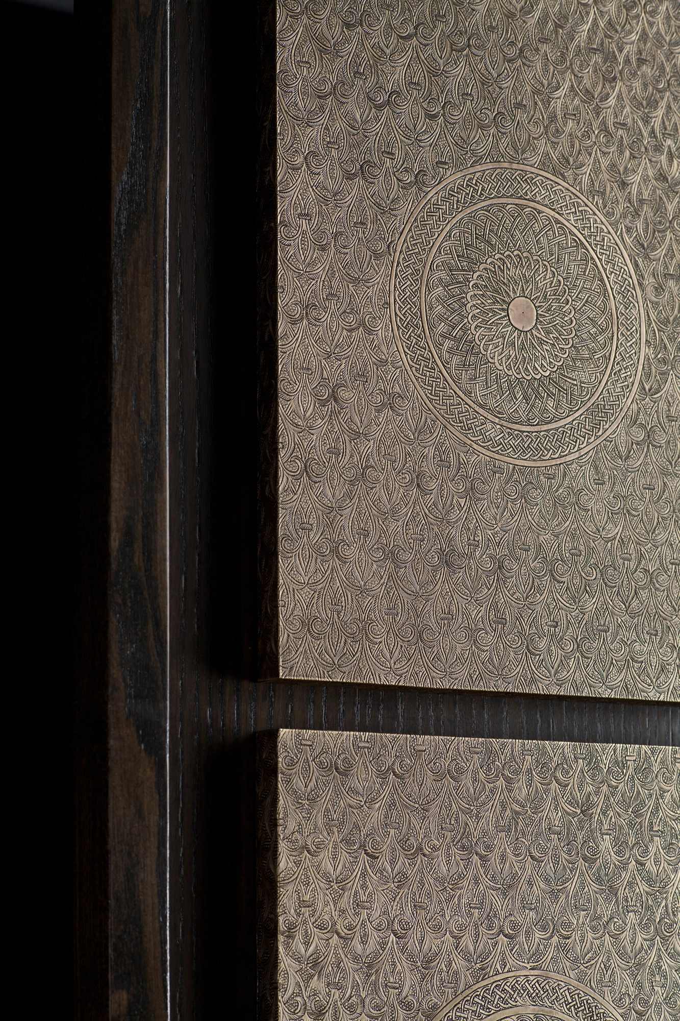 Close-up of pale engraved medallion panels separated by dark wooden dividers.