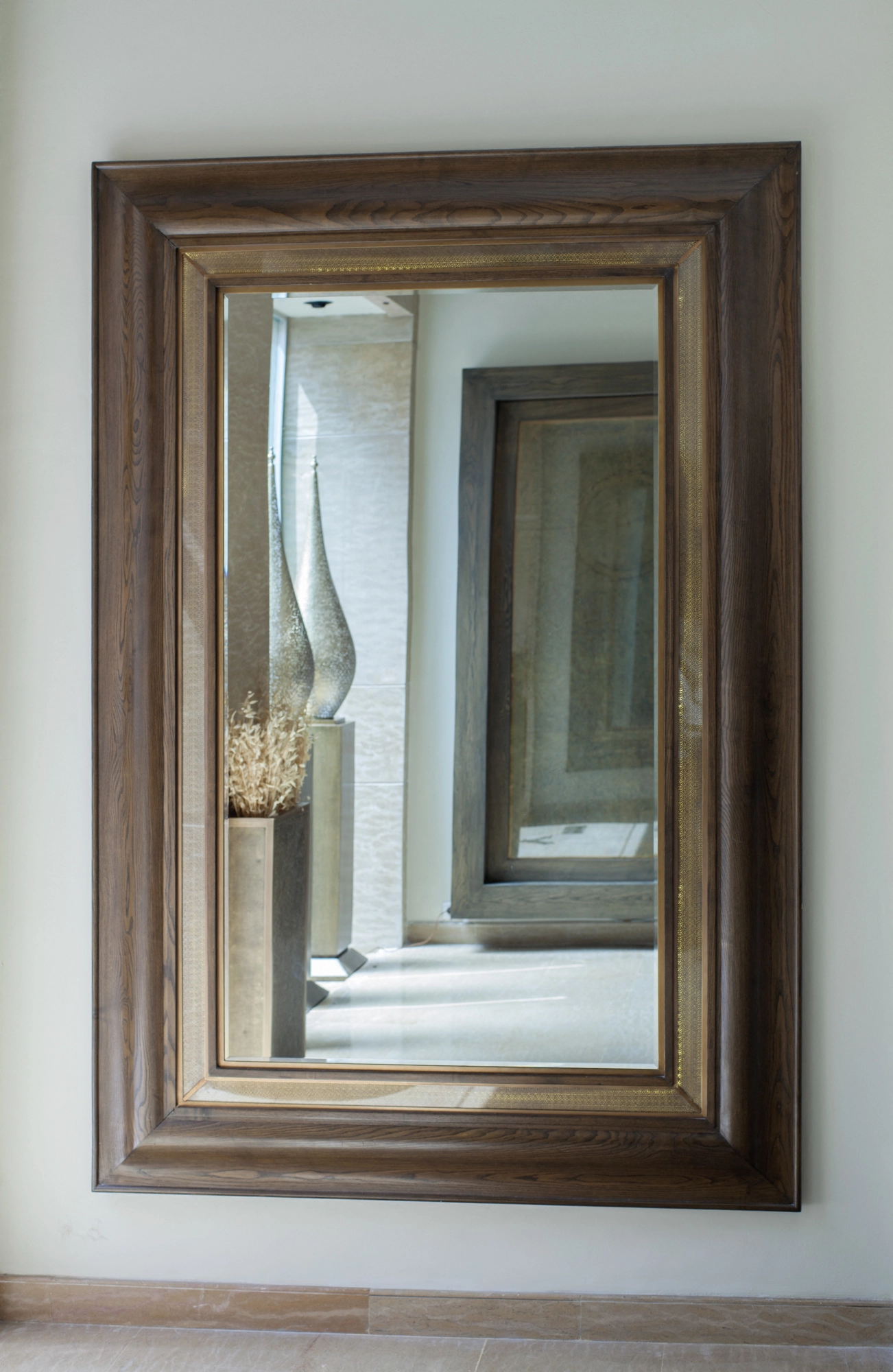 A rectangular mirror in a wooden frame reflecting a colonnaded hallway receding into the distance.