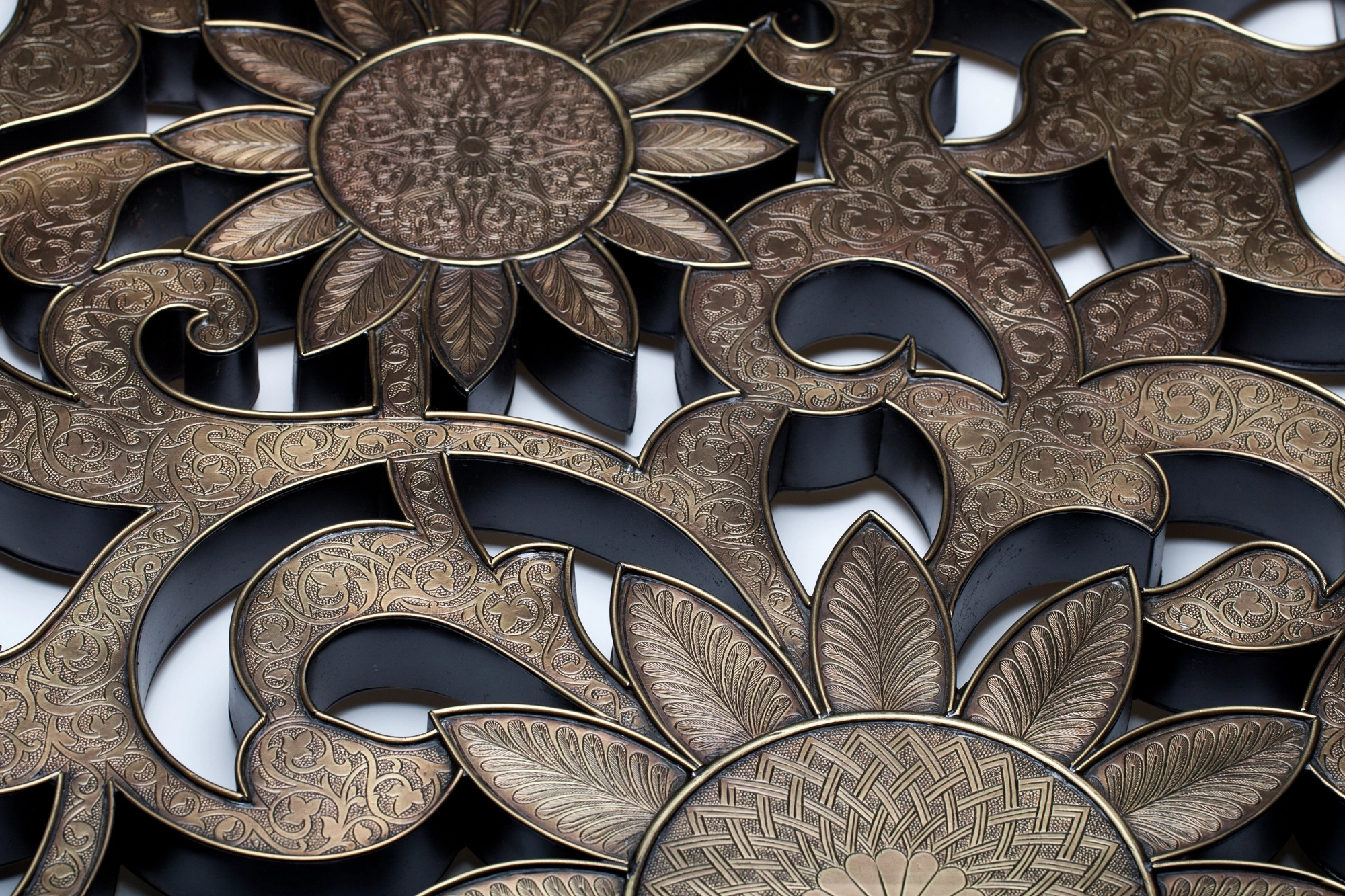 Close-up of a silver openwork wall-art panel carved with sunflowers and scrolling foliage.