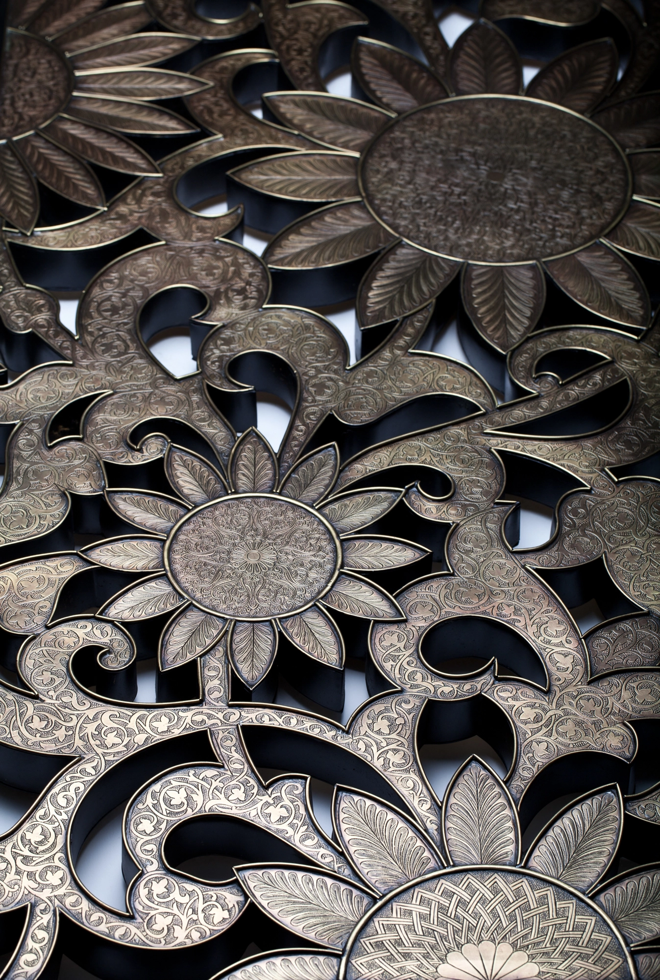 Angled view of a silver floral openwork panel set with engraved oval medallions.
