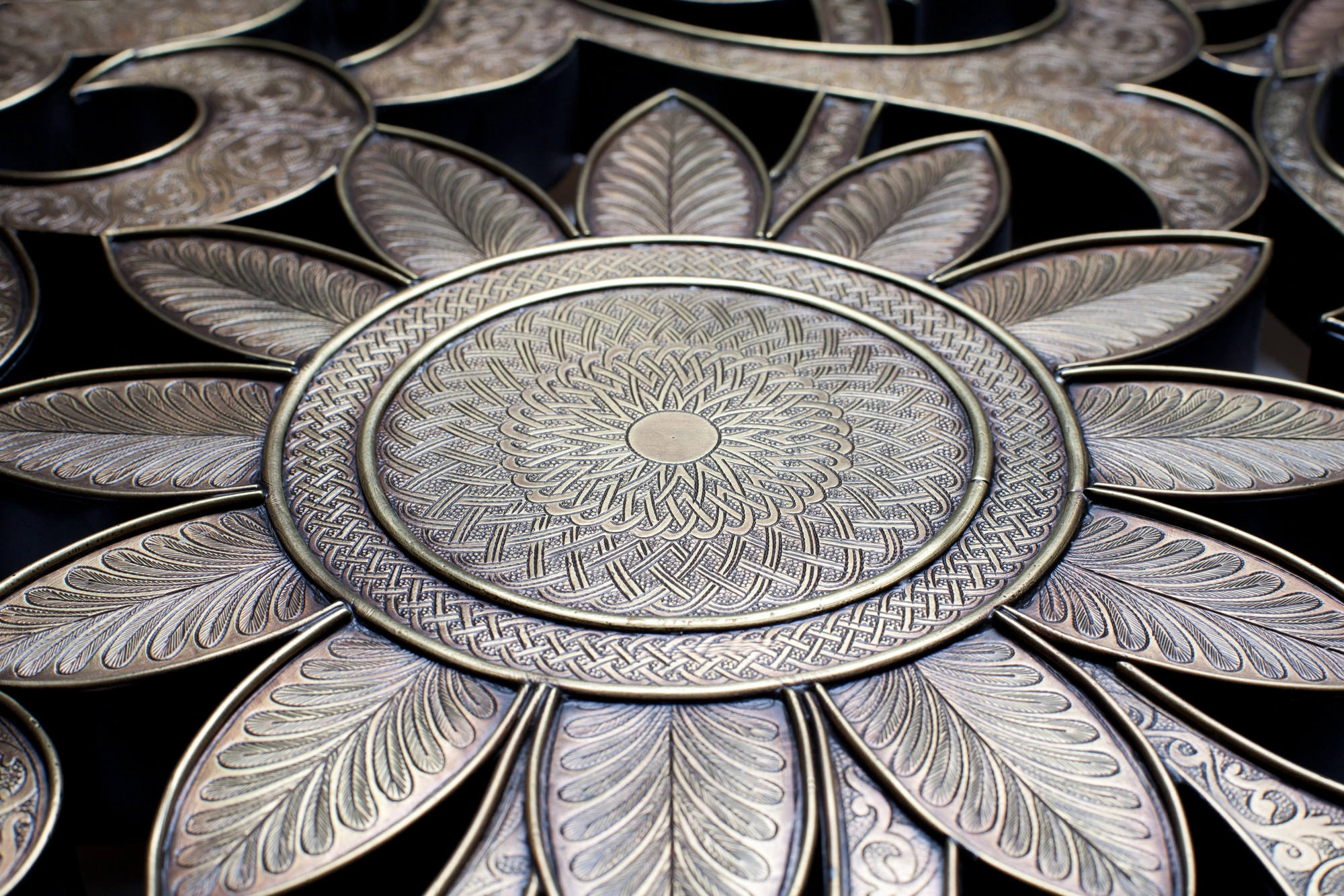 Close-up of an engraved silver sunflower medallion within a floral openwork panel.