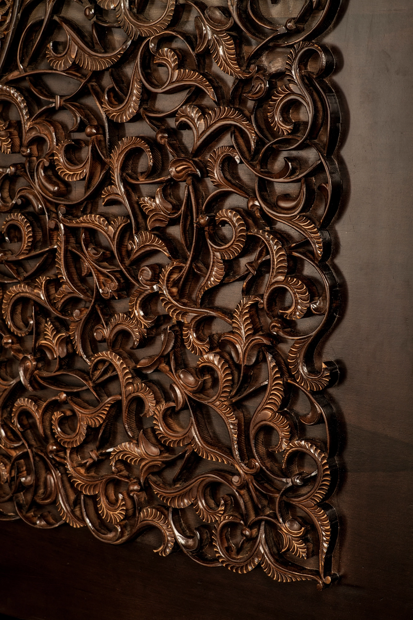Close-up of densely carved dark-wood foliage scrollwork covering a wall panel.
