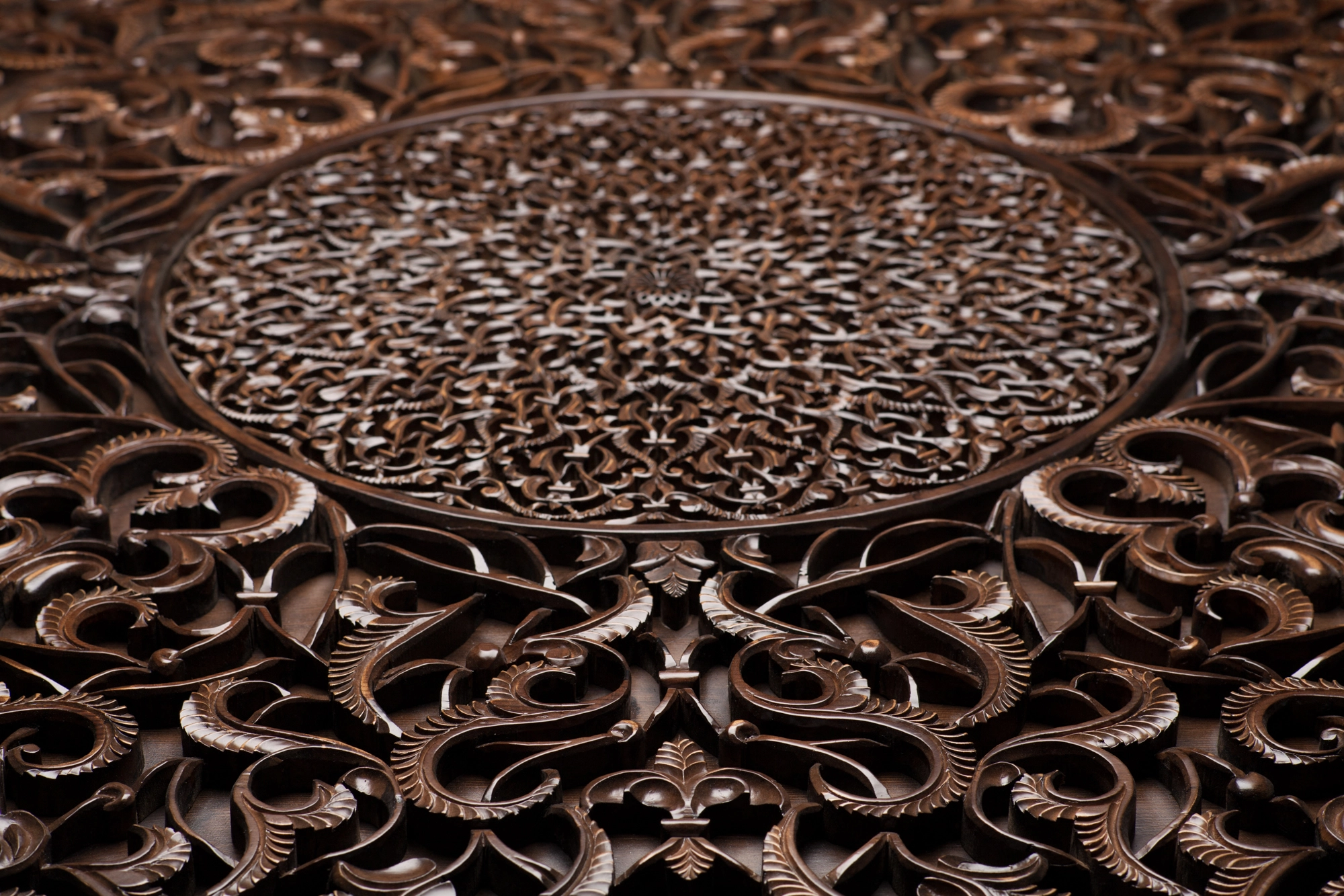 Close-up of a carved dark-wood circular medallion amid dense foliage scrollwork.