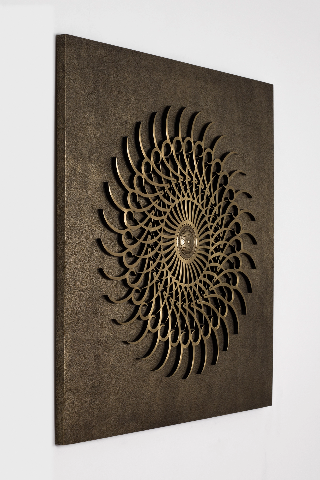 An angled view of a dark panel bearing a golden spiral sunburst of swirling calligraphy.