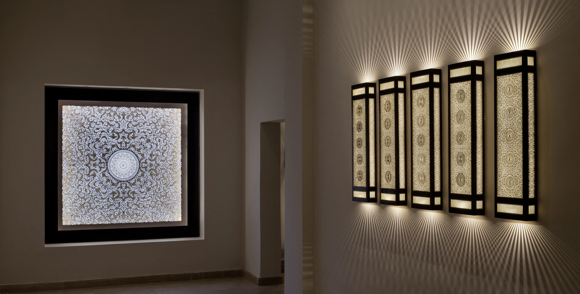 A wide hallway view with a framed backlit panel and a row of tall illuminated openwork panels along the wall.