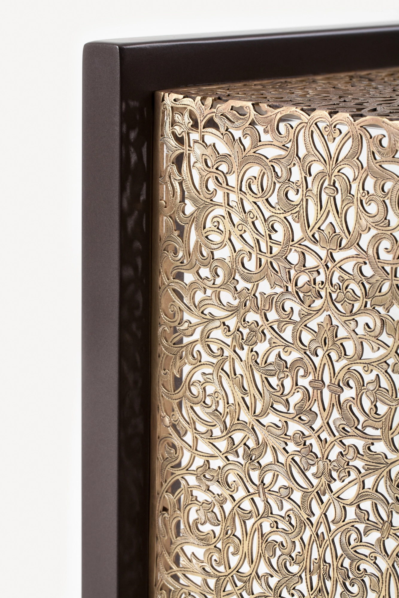 Close-up of a console table's pierced golden side panel set within its dark wooden frame.