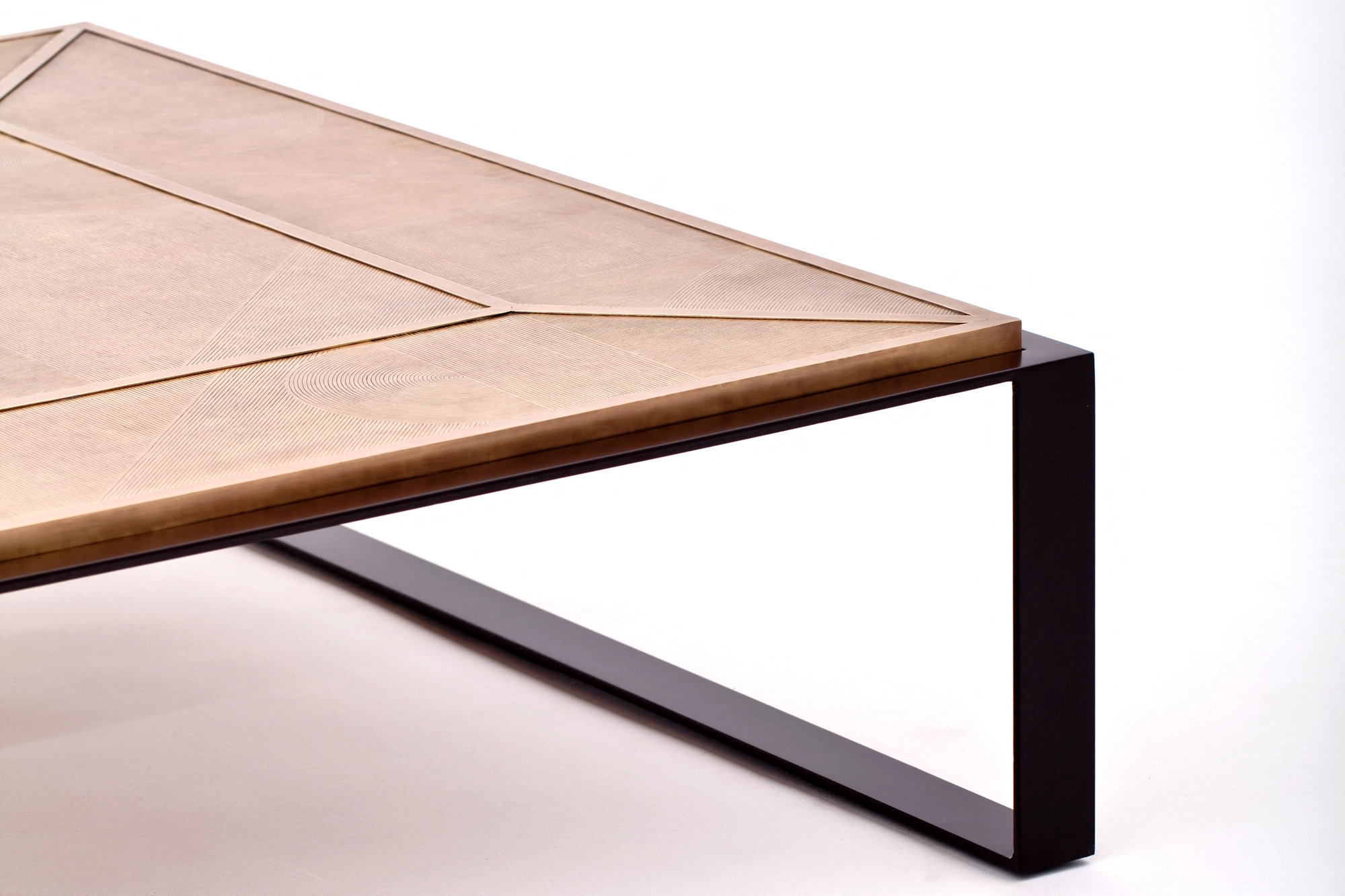 Close-up of a coffee table's woven inlay top and the dark metal leg supporting its corner.