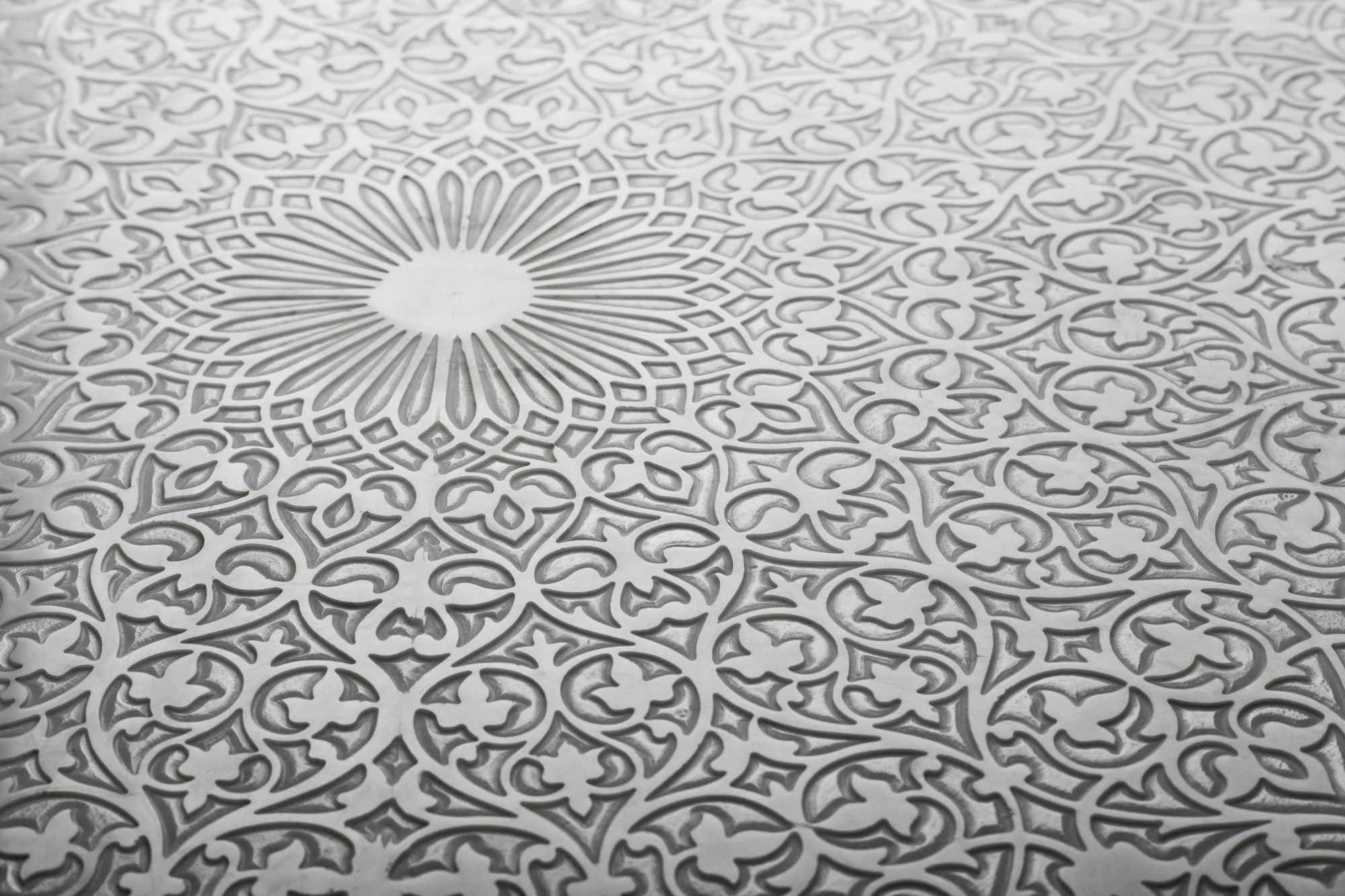 Close-up of a pale engraved tabletop worked with a radial medallion pattern.
