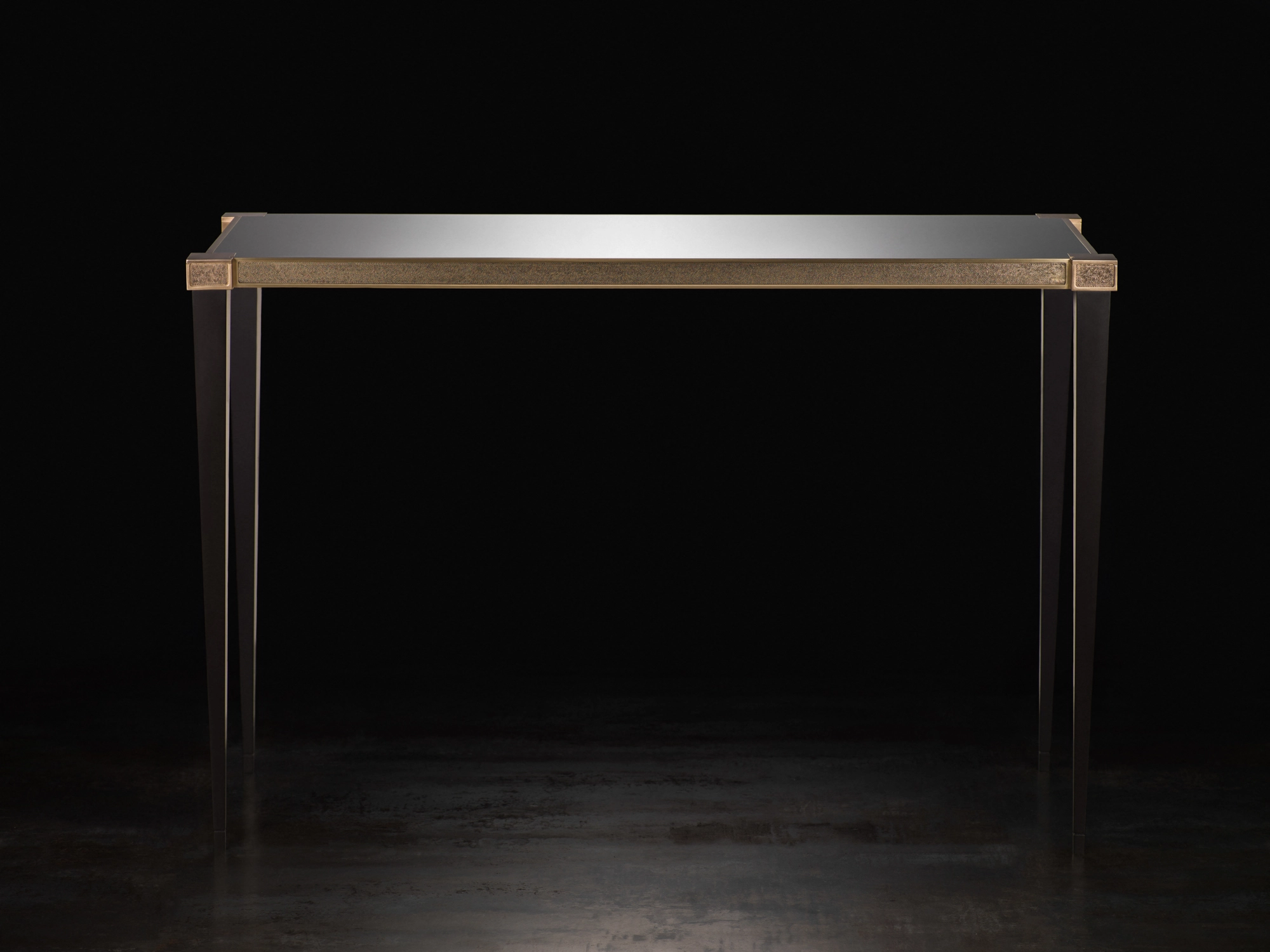 A console table with a dark top and slim brass-edged frame, photographed against a black background.