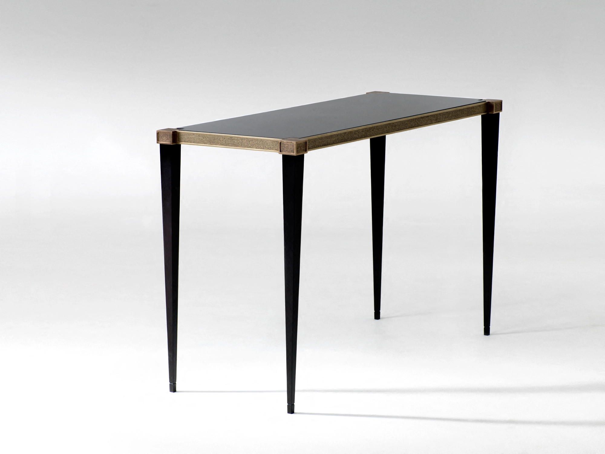 A console table with a dark top on slim tapered legs, photographed against a pale grey background.