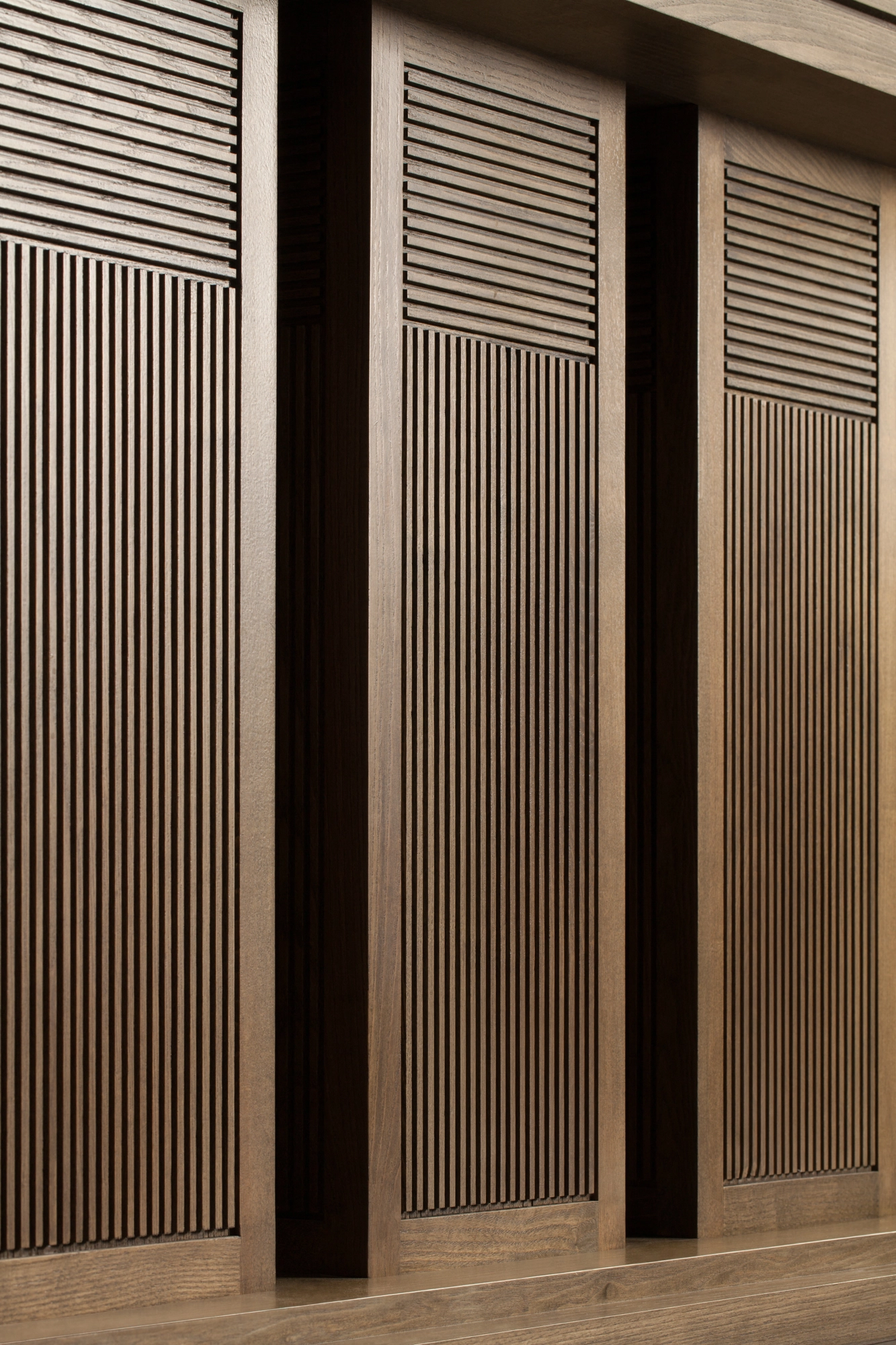 Tall vertical slatted wooden panels lit warmly to show their fine ribbed texture.