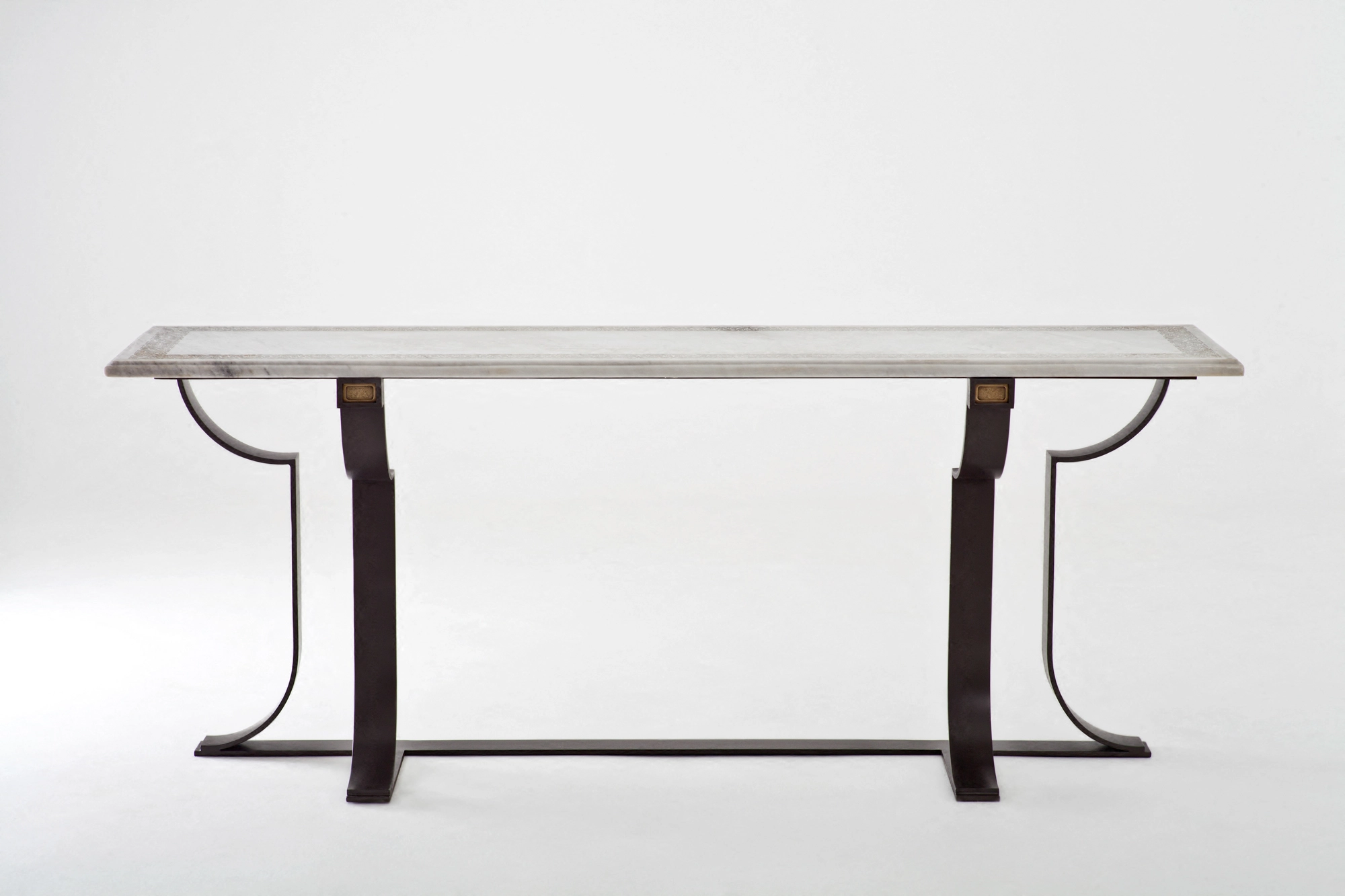 A console table with a pale carved stone top on curved dark metal legs, photographed against a white background.