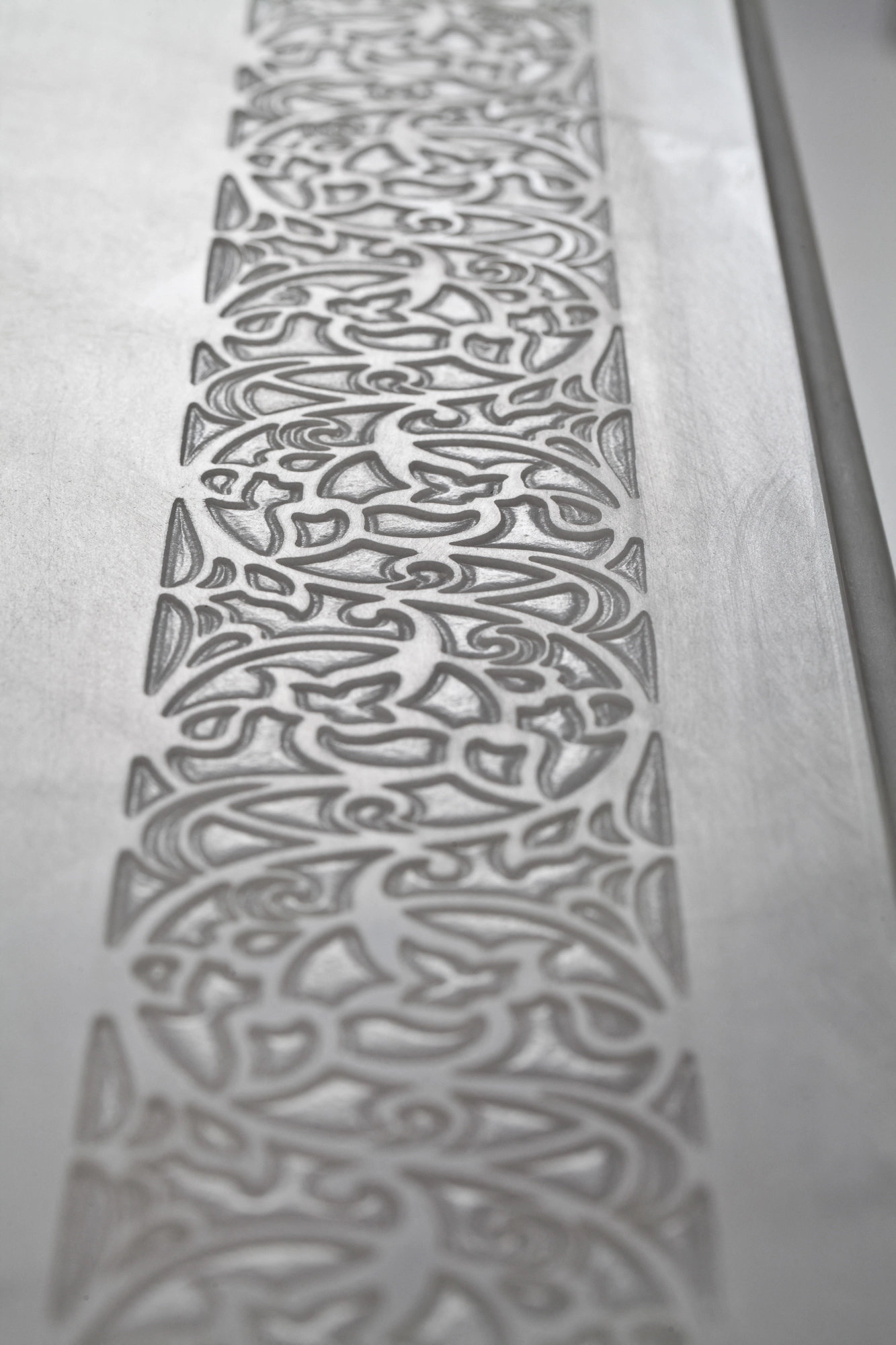 Close-up of a console table's pale stone top edge carved with a flowing openwork pattern.