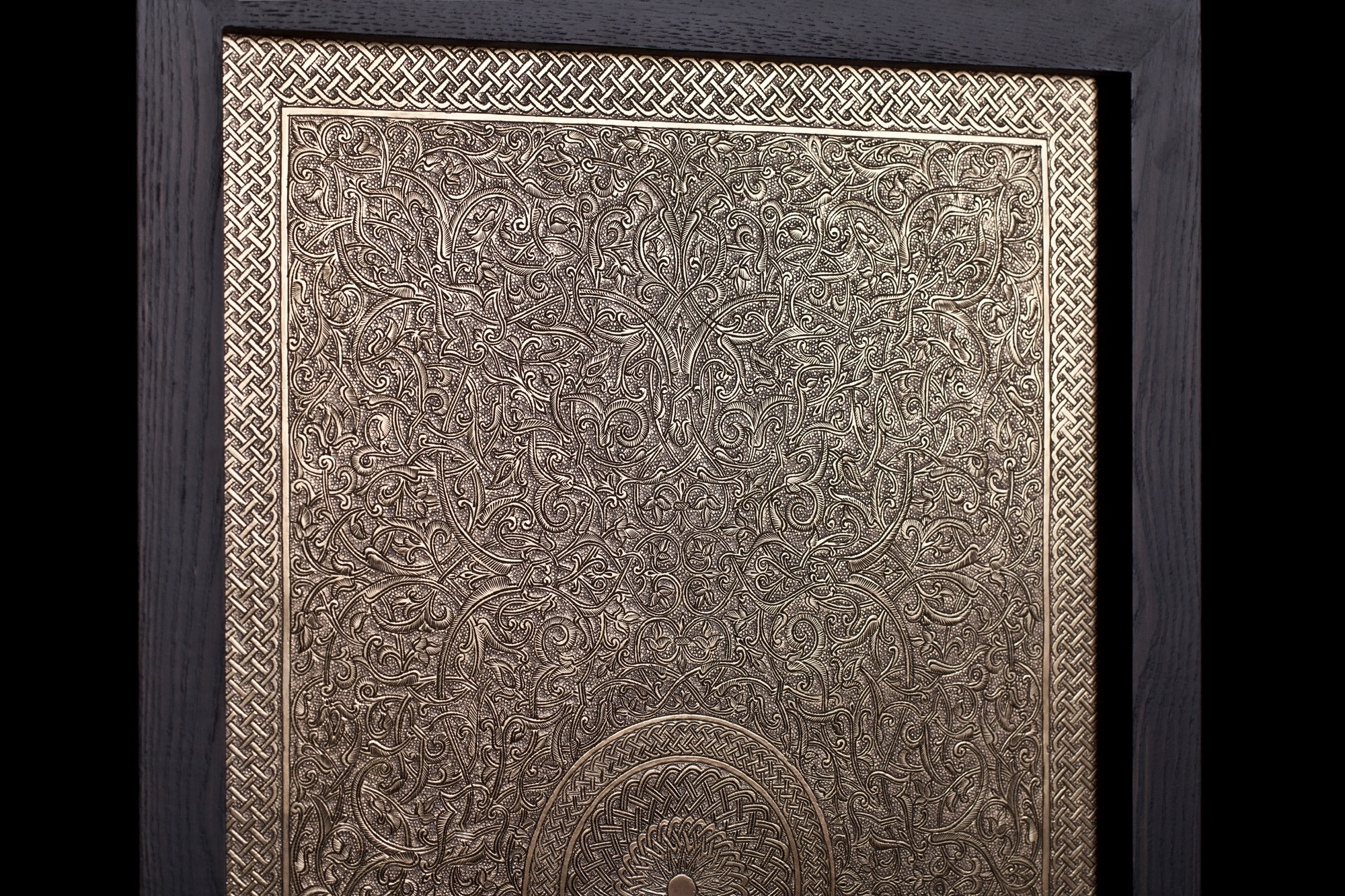 A framed engraved bronze panel centred on a circular medallion, set in a dark surround.