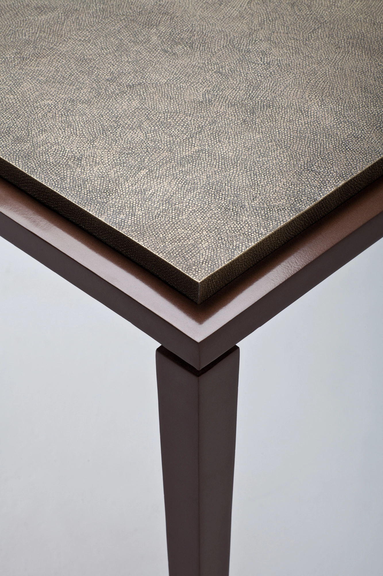 Corner detail of a console table with a textured grey top and a dark wood edge.