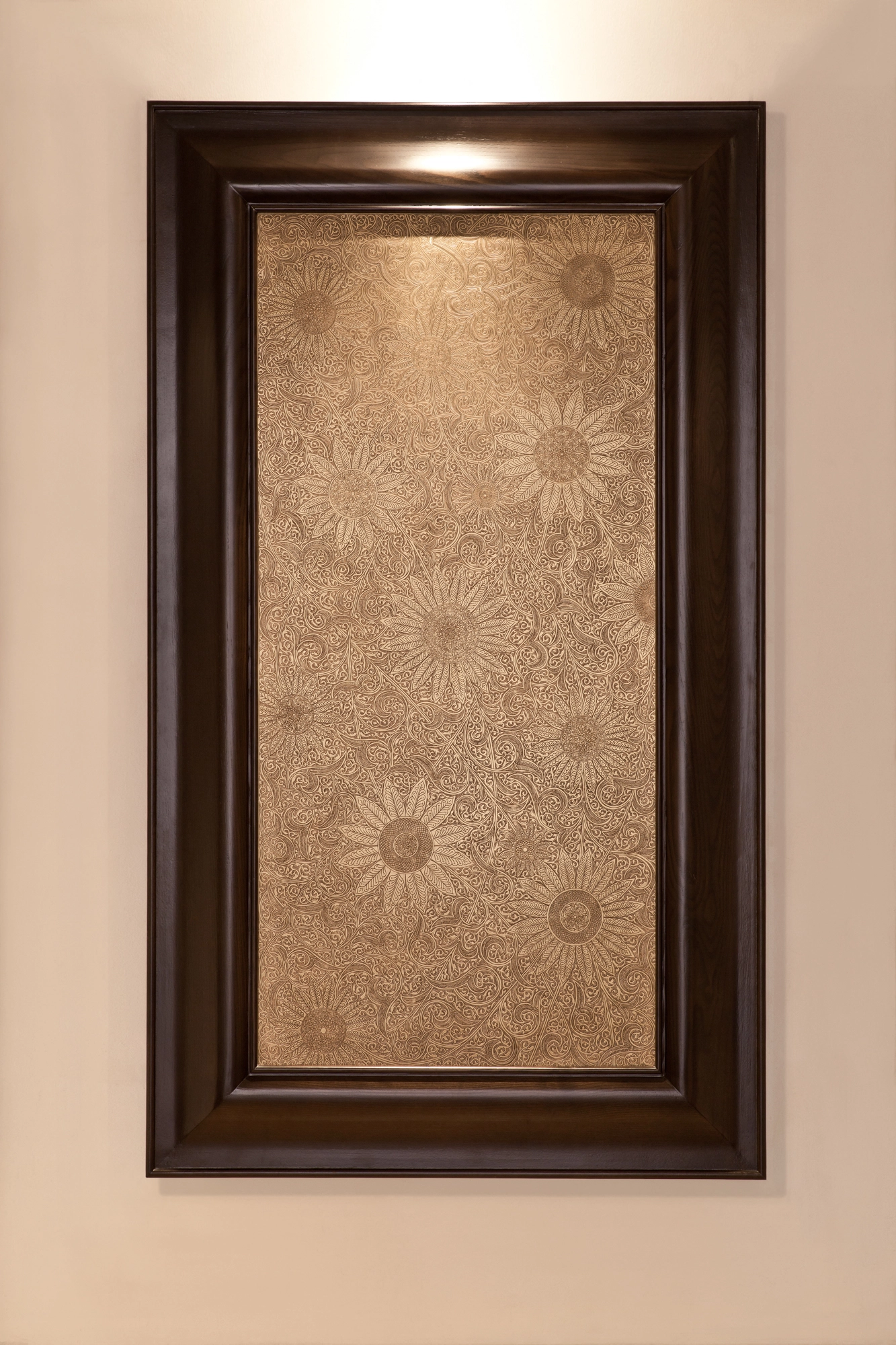 A tall dark-framed wall panel with a pale engraved sunflower-and-foliage ground, downlit.