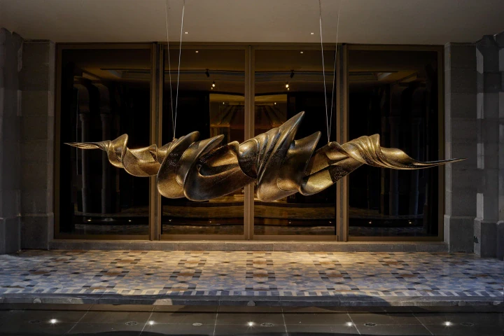 A long bronze dragon sculpture suspended in a grand, dimly lit hall.