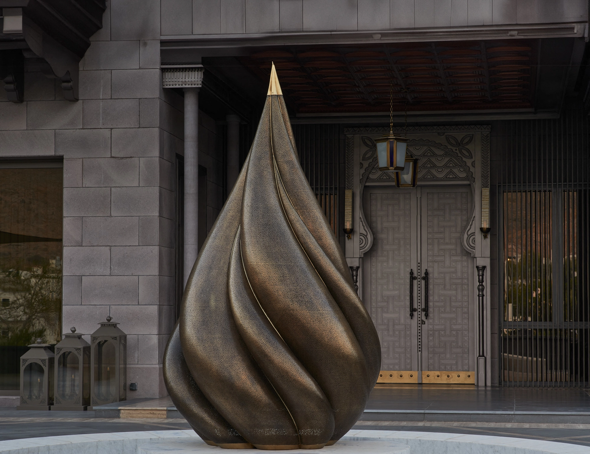 The brass flame lotus sculpture before a stone building's grand doorway in daylight, Parametric Lotus.