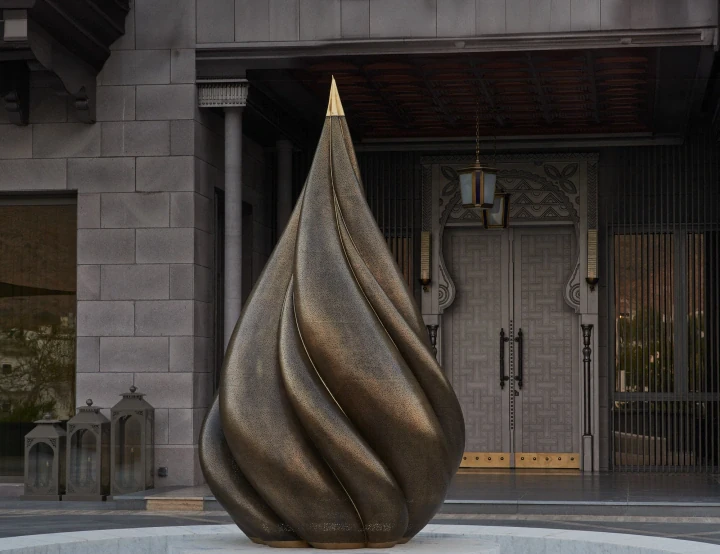 The brass flame lotus sculpture before a stone building's grand doorway in daylight, Parametric Lotus.